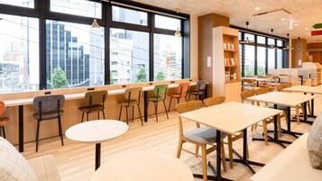 Un interior moderno con amplios ventanales, suelo de madera y diversas opciones de asiento, incluidas mesas y sillas.