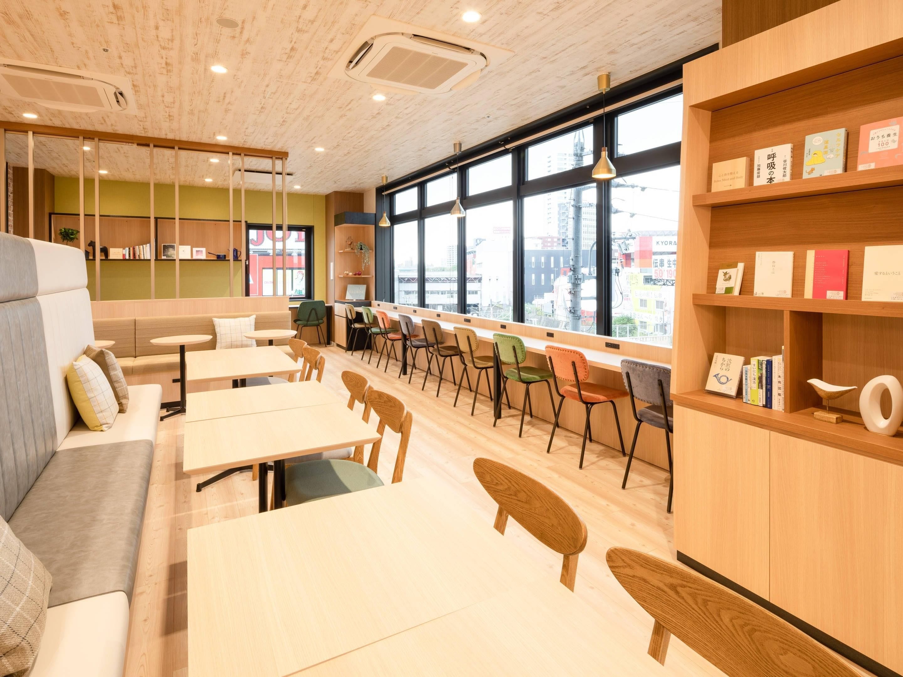 Ein modernes Café mit Holzmöbeln, einer Sitzgelegenheit und Blick auf die Stadt durch große Fenster.