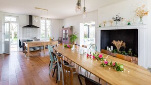 A spacious kitchen with a wooden dining table, chairs, and a fireplace.