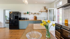 A modern kitchen with a wooden island, black refrigerator, and a vase with flowers.