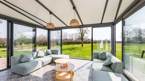 A modern living room with large windows, a patterned floor, and a sectional sofa.