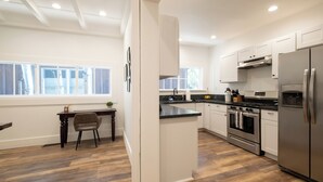 A modern kitchen with a central island, stainless steel appliances, and a view of the outside. - Pet-Friendly Chic Downtown Home w/ Queen Suite & Desk | Near River & Bike Trails (Truckee)