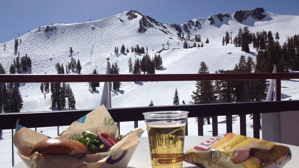 A table with a bag of chips, a drink, and a sandwich, overlooking a snowy mountain landscape. - Pet-Friendly Chic Downtown Home w/ Queen Suite & Desk | Near River & Bike Trails (Truckee)