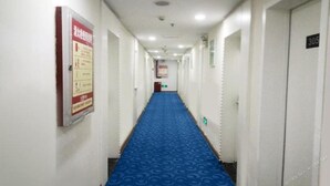 Un pasillo de hotel con alfombra azul, paredes blancas y puertas numeradas 305 y 306.