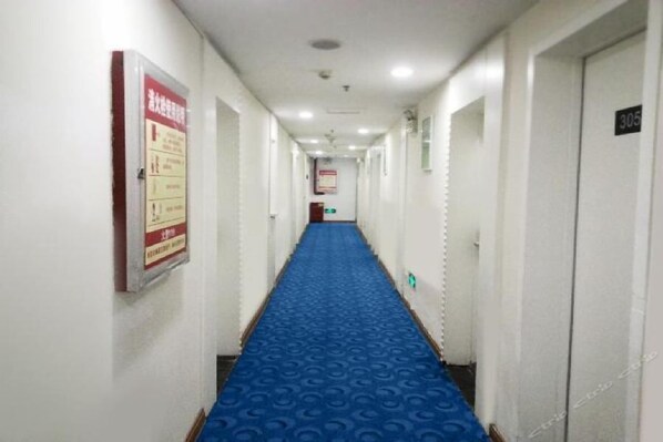A hotel hallway with a blue carpet, white walls, and doors numbered 305 and 306. - 7 Days Inn (Qiannan)