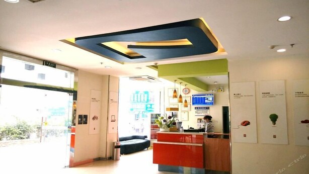 A reception area with a modern design, including a large geometric ceiling feature, a reception desk, and a seating area. - 7 Days Inn (Qiannan)