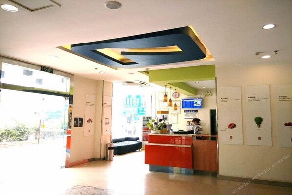 A reception area with a modern design, including a large geometric ceiling feature, a reception desk, and a seating area. - 7 Days Inn (Qiannan)