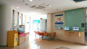 Un vestíbulo moderno y limpio con una recepción, zona de estar y carteles informativos.
