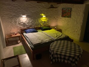 Ein gemütliches Schlafzimmer mit einem Bett, einer Bank und einem kleinen Tisch mit einer Kerze.