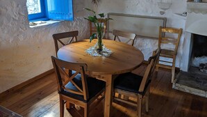 A rustic dining area with a round wooden table, four chairs, and a hanging light fixture. - Arcadia, an idyllic, original, traditional farmhouse (Tyros)
