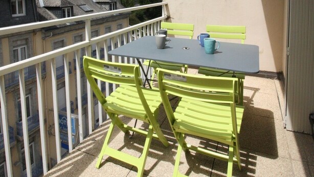 A balcony with a table and chairs, overlooking a mountainous landscape. - Appartement en Centre Ville Avec Terrasse Exposée Ouest (Cauterets)