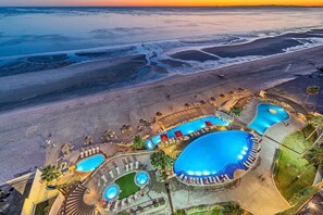 An aerial view of a resort with multiple swimming pools, a beach, and a sunset. - Oceanfront Paradise at Sonoran Sky – Stunning 3BR Condo, Pools, Water Slide & Unmatched Luxury! (Puerto Peñasco)