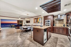 A spacious kitchen with a large island, granite countertops, and a view of the ocean.