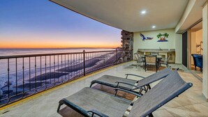 Un balcon avec vue sur la mer, un coin repas avec des chaises et une table, et un mur en pierre.