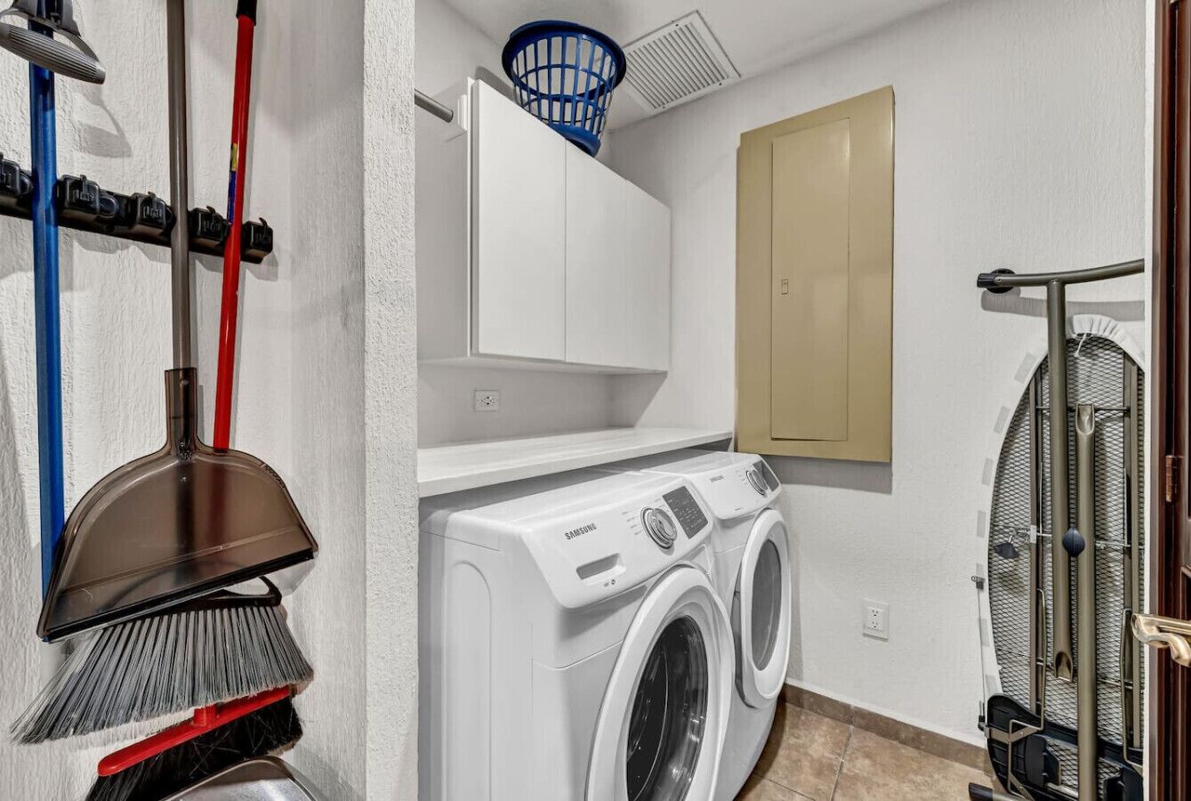 Un espace buanderie comprenant un lave-linge, un étendoir et un meuble fixé au mur.