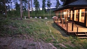 Une terrasse en bois avec un chemin de pierre menant à un chalet doté d’une porte en verre.