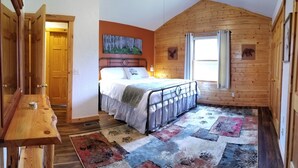 Une chambre à coucher avec un lit, une tête de lit en bois, une fenêtre avec des rideaux, une porte en bois et un tapis.