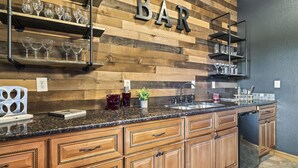 A kitchen with wooden cabinetry, a granite countertop, and a 'BAR' sign above the shelves. - Game Rooms + Views: Spacious Mtn Cabin in Murphy! (Murphy)