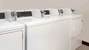 A row of white, modern laundry machines with control panels and a digital display. - Courtyard Hotel & Event Center (Crockett)