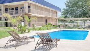 A building with a pool and lounge chairs. - Courtyard Hotel & Event Center (Crockett)