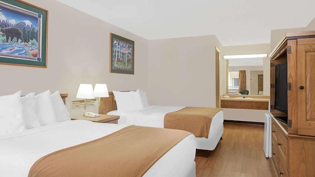 A hotel room with two beds, a television, a mirror, and artwork on the walls. - Courtyard Hotel & Event Center (Crockett)