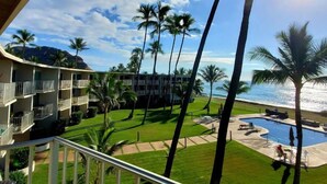 Un hôtel doté de nombreux balcons donnant sur une piscine, des palmiers et offrant une vue sur l’océan.