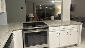 A modern kitchen with white cabinets, a stainless steel stove, and a granite countertop. - 3 bed 2 bath, Heated Private POOL, Ft Myers near Cape Coral Bridge  (Fort Myers)