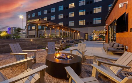 A rooftop patio with Adirondack chairs, a fire pit, and a covered seating area.