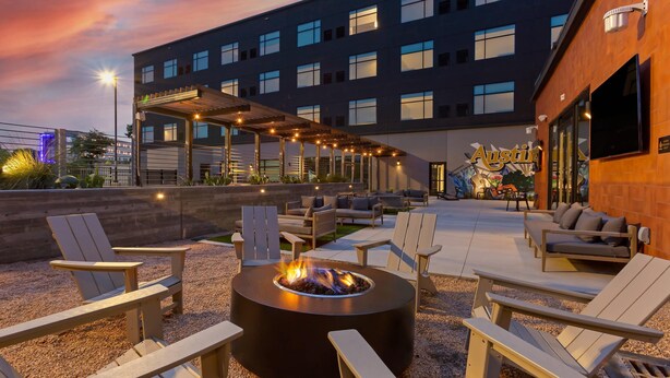 Un patio en la azotea con sillas Adirondack, una chimenea y una zona de estar cubierta.