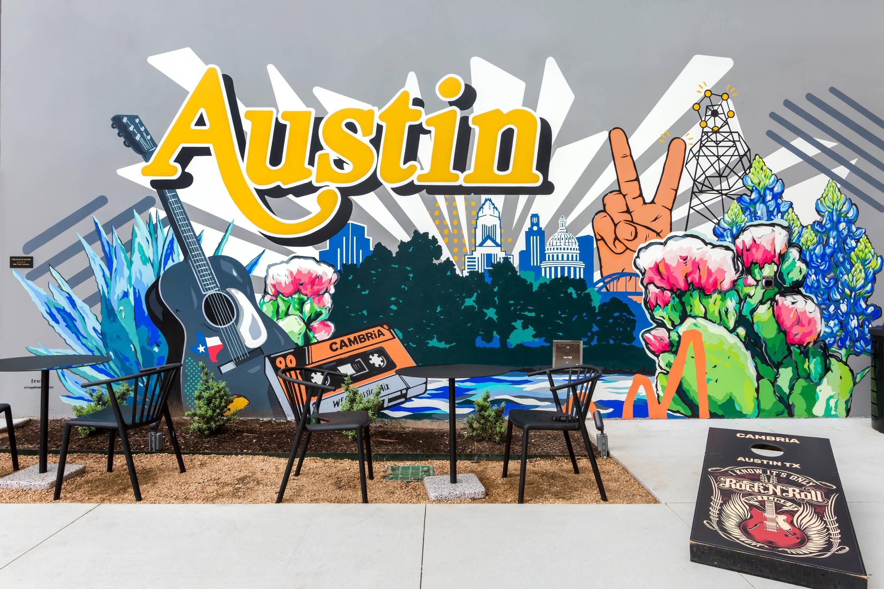 Un mural que muestra destacadamente 'Austin', una guitarra, un símbolo de paz y el perfil de una ciudad.