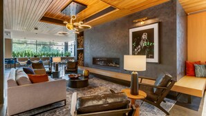 Un interior moderno con un sofá, sillones de cuero, una chimenea y una zona de comedor con sillas y mesas.
