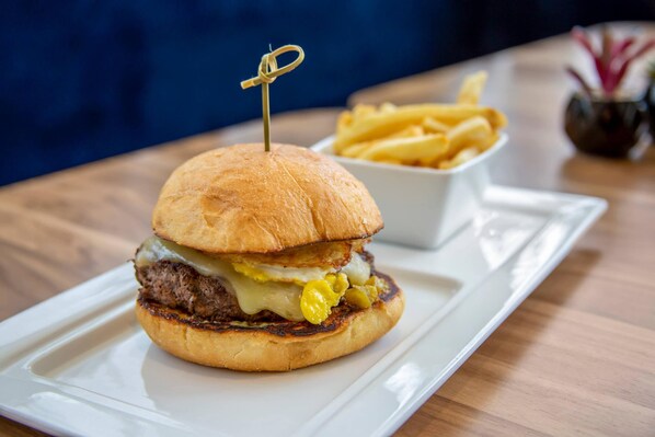 A sandwich with a toothpick on a white plate, accompanied by a bowl of fries.