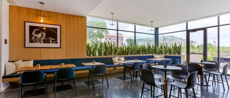 Un espace de restauration moderne, doté d’un long banc, de plusieurs tables et de chaises.