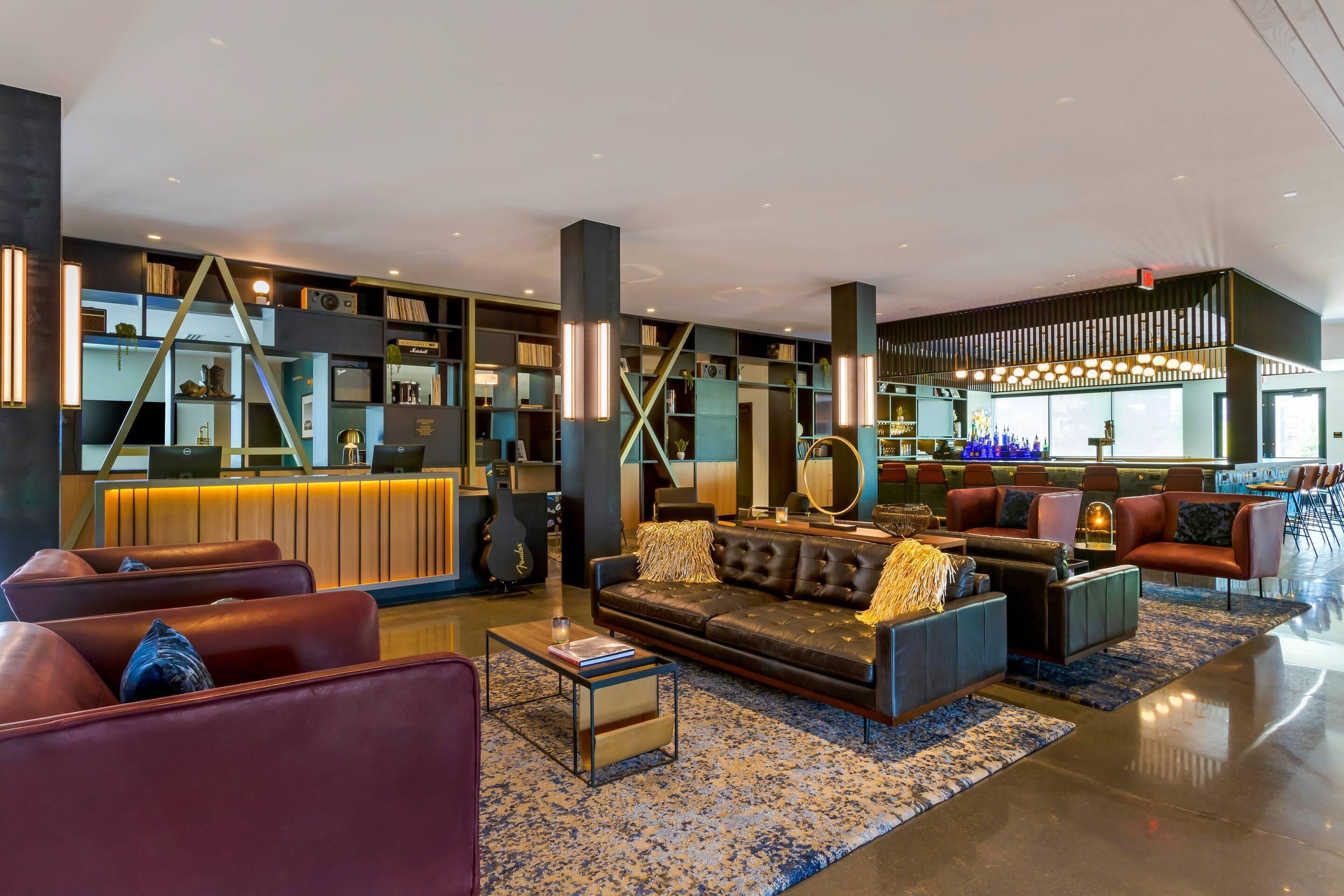 A modern lobby with leather sofas, a reception desk, and a bar area.