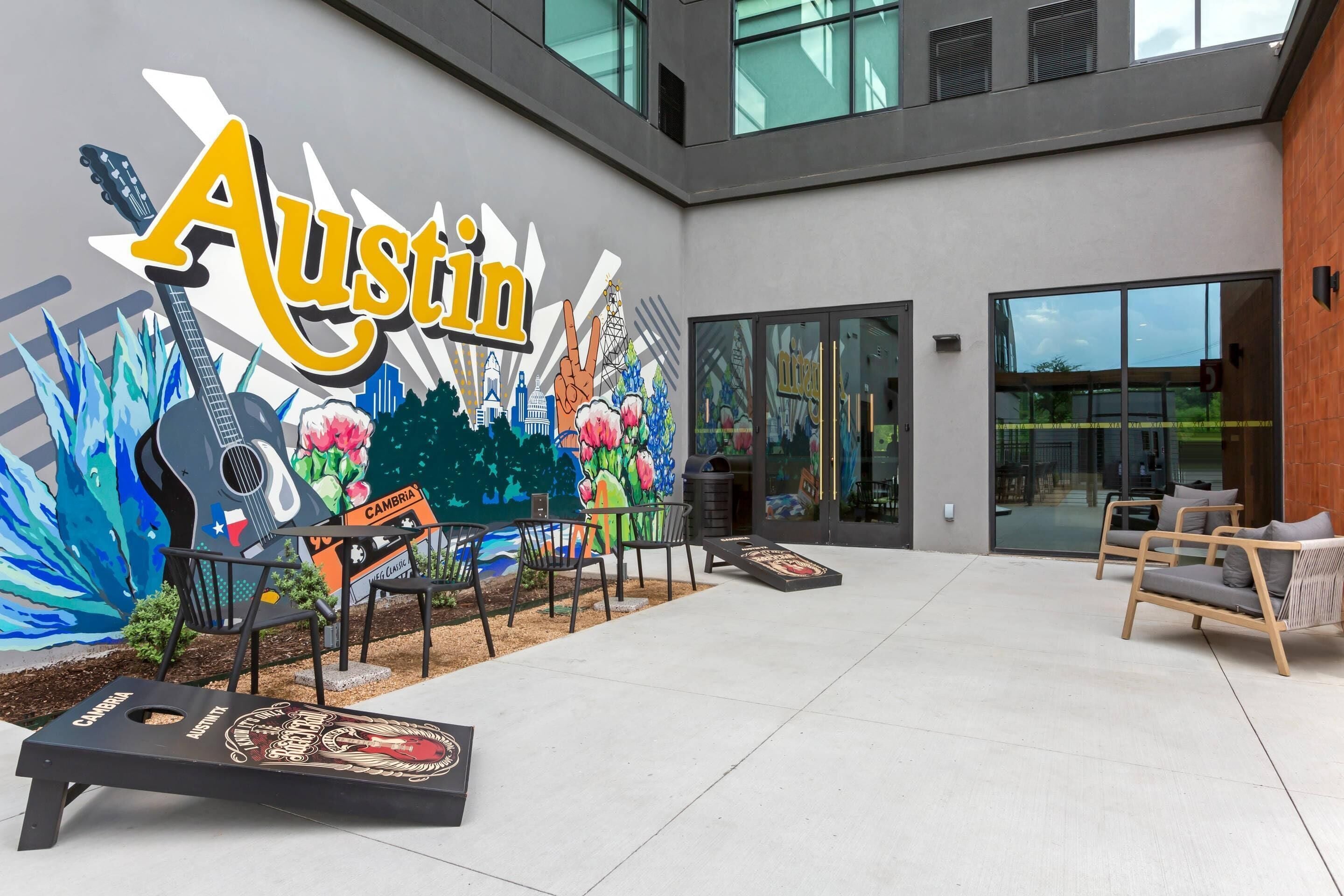 Une cour intérieure ornée d’une fresque murale, dotée d’un espace pour s’asseoir à l’extérieur et d’une enseigne indiquant « Austin ».