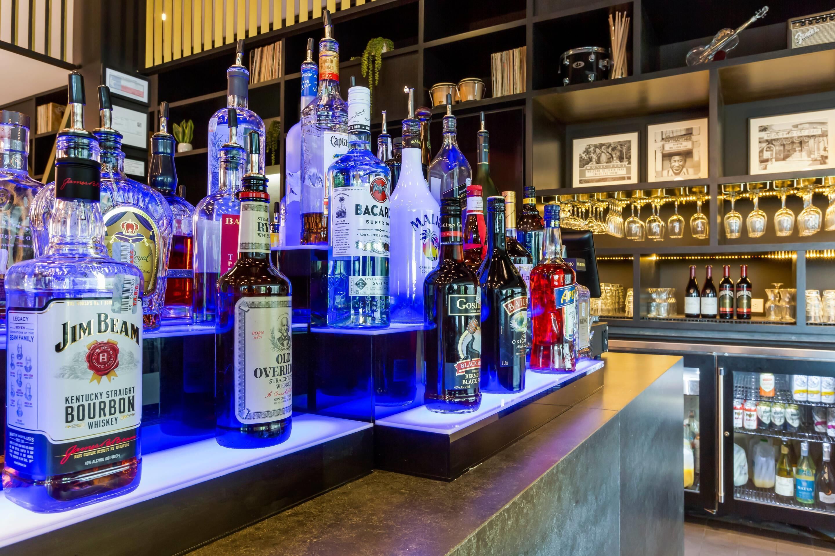 Un espace bar avec différentes bouteilles d’alcool et un présentoir réfrigéré.