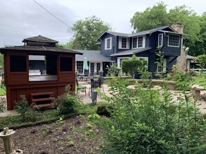 Ein zweistöckiges Haus mit einem Steinofen, einer hölzernen Laube und einer Terrasse mit Gartenmöbeln.
