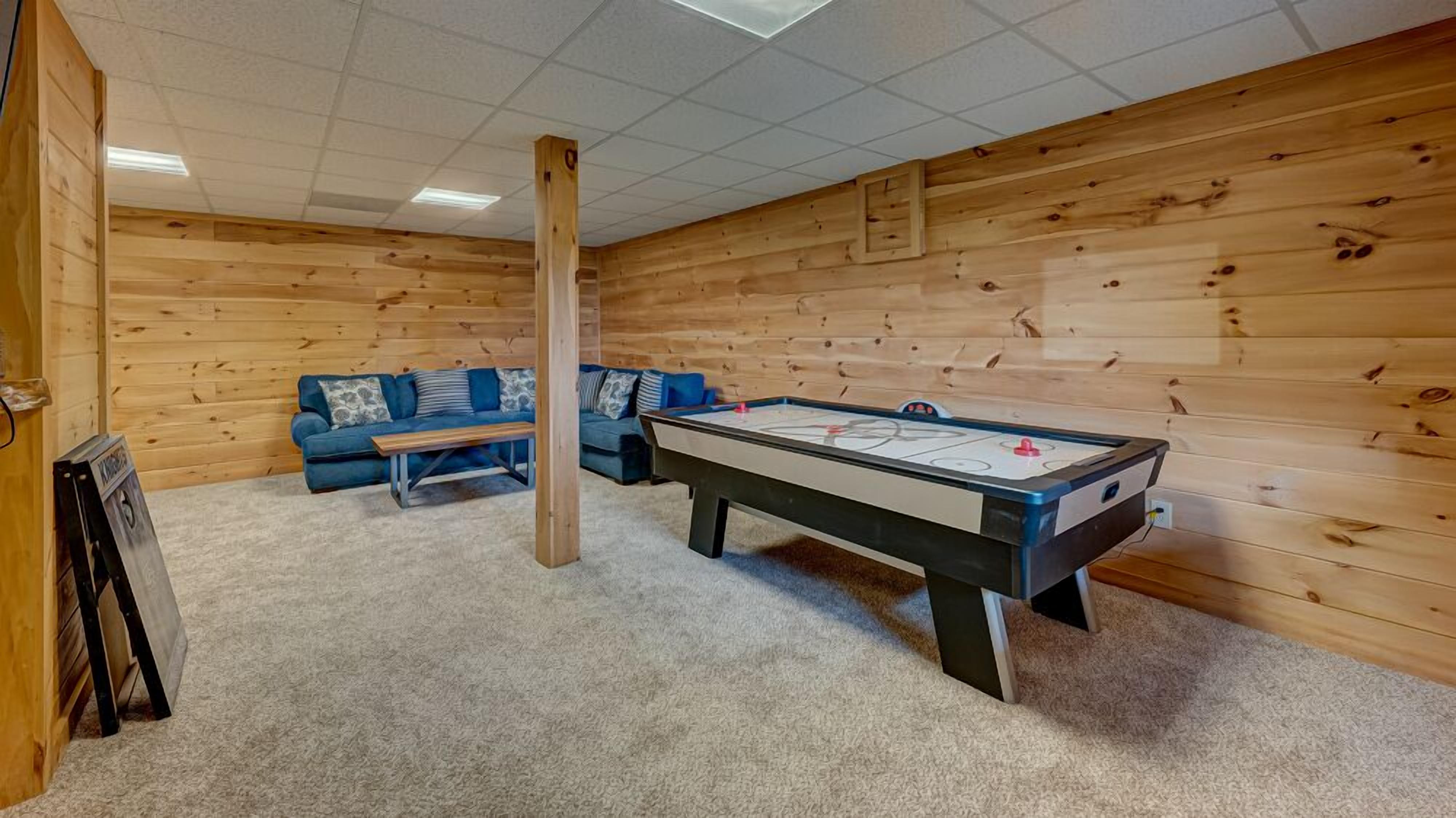 A room with a pool table, a blue sofa, and wooden walls.
