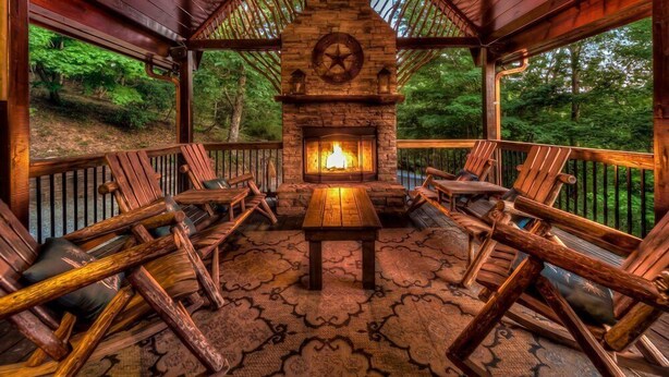 Eine Holzterrasse mit Kamin aus Stein, umgeben von Holzstühlen und einem Tisch.