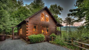 Eine Blockhütte mit Veranda, umgeben von dichtem Wald.