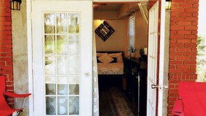 A room with a bed, a small table, and a chair. There is a door leading to another room. - Private, Sanitized Loft, with Discounts Sleeps 2 (Lynchburg)