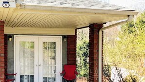 A covered porch with a white door, a red chair, and a small table. - Private, Sanitized Loft, with Discounts Sleeps 2 (Lynchburg)