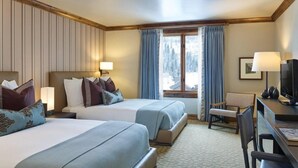 Ett hotellrum med två sängar, ett skrivbord, en stol och en tv.