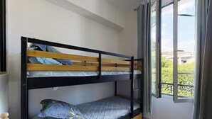 A bunk bed with a wooden headboard, a lower bunk with a mattress and pillows, and a window with curtains. - Suite Riviera Five stars Holiday house (Beaulieu sur mer)