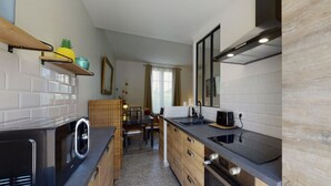 A modern kitchen with white subway tiles, wooden cabinets, a black countertop, and a built-in oven. - Suite Riviera Five stars Holiday house (Beaulieu sur mer)