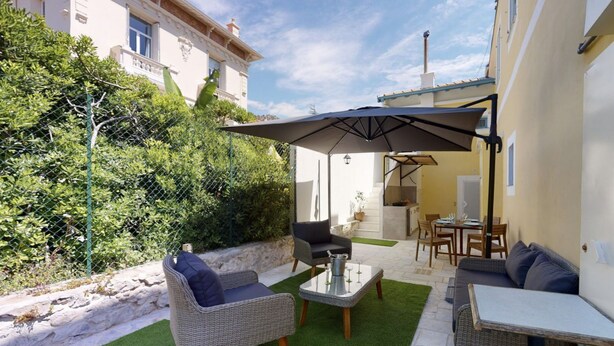 A patio area with wicker furniture, a table with a glass top, and a large umbrella providing shade. - Suite Riviera Five stars Holiday house (Beaulieu sur mer)