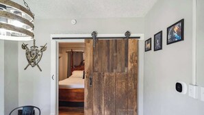 Een kamer met een houten schuifdeur, een bed, een kroonluchter en lijstwerken aan de muur.
