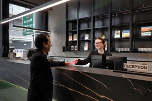 A reception desk with a sign indicating 'Airport Seaport Lane' and a 'RECEPTION' sign. - The Viv Hotel Wellington (Wellington)