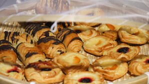 A basket of assorted pastries, including chocolate-covered and berry-topped varieties.