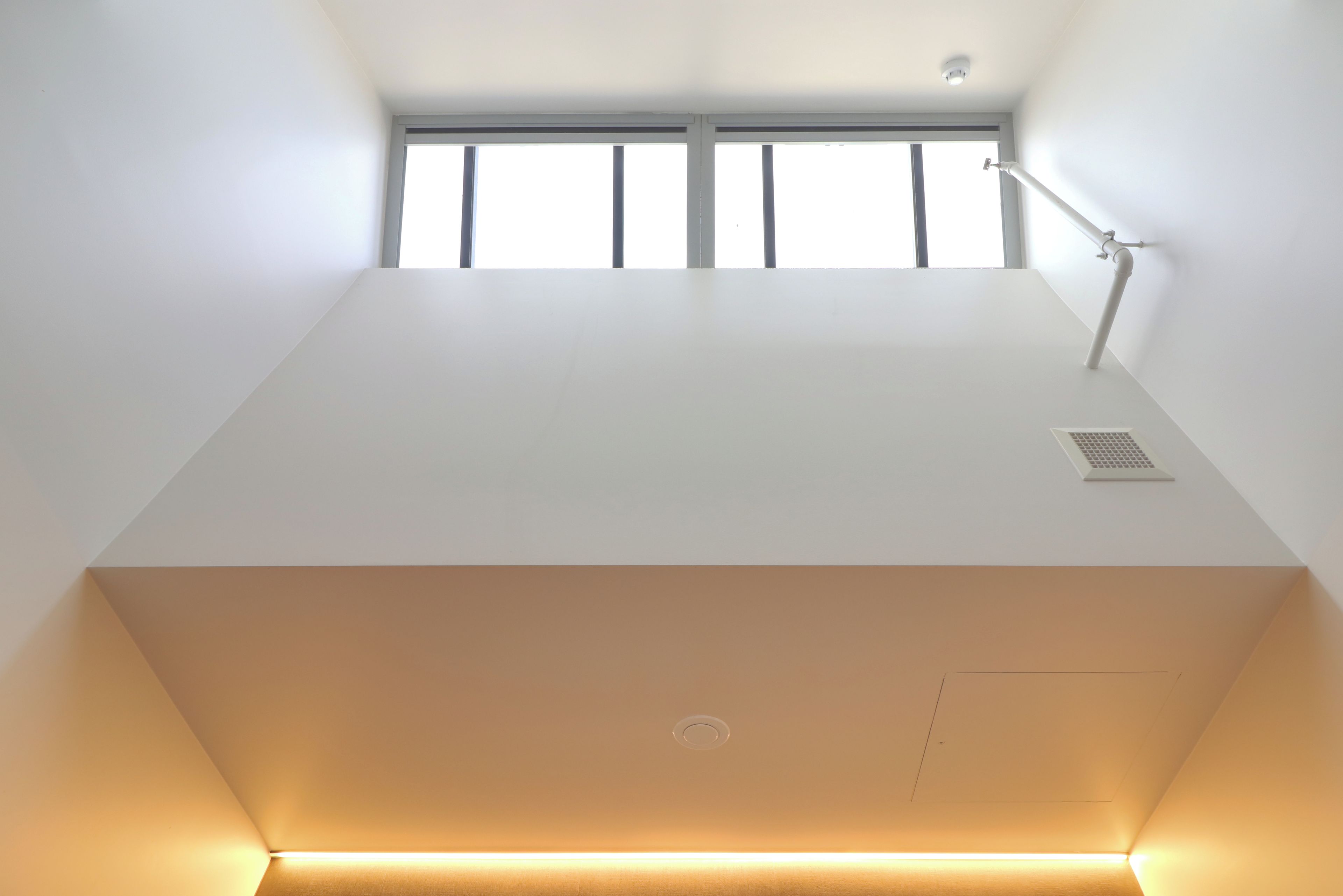 A modern, minimalist room with a large window, a desk, and a chair.
